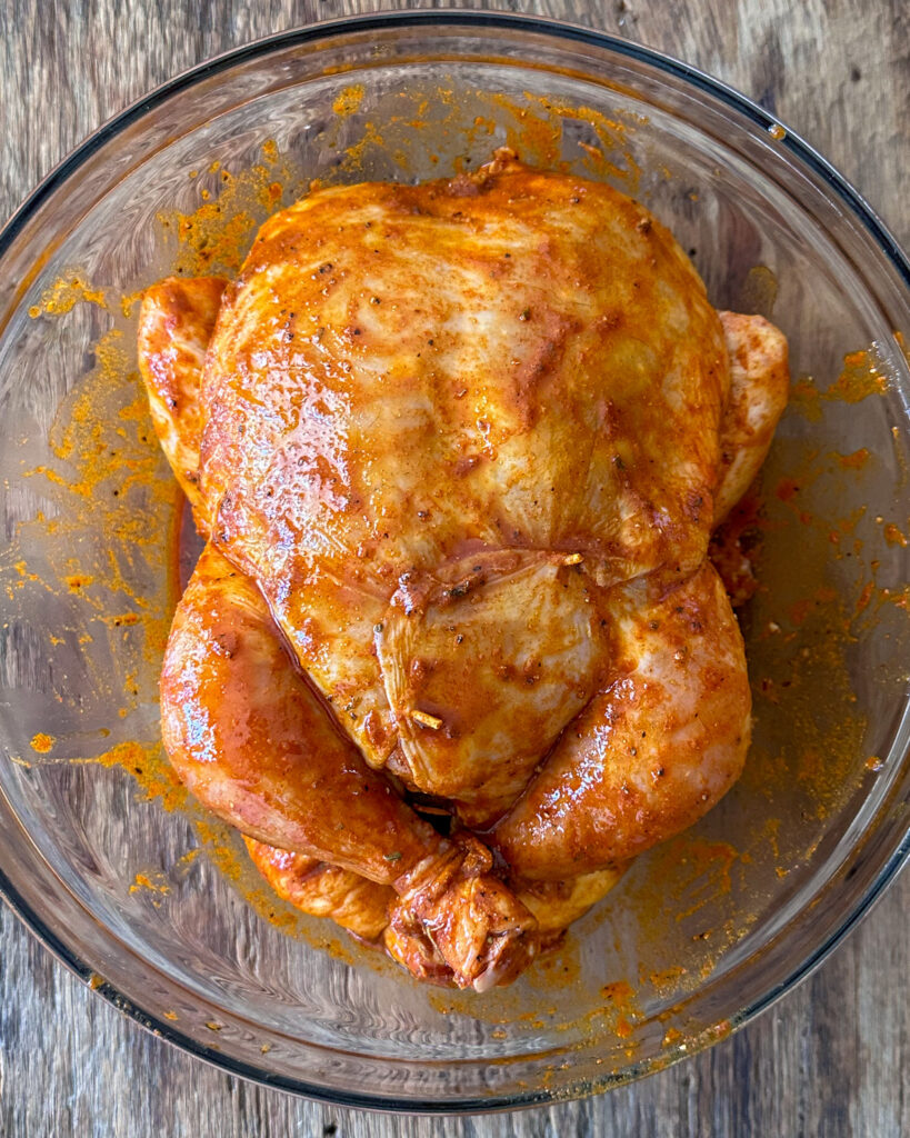 A chicken marinating in a bowl.