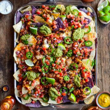 A tray of colourful and loaded cheesy chili nachos.