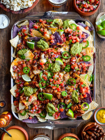 A tray of colourful and loaded cheesy chili nachos.