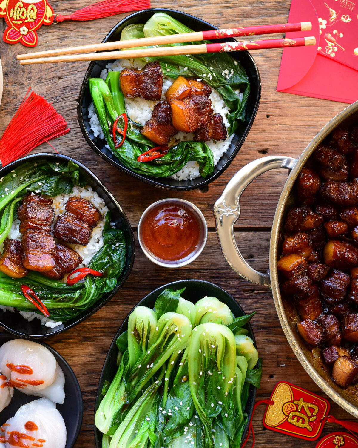 Two bowls of Chinese style braised pork belly served with steamed rice and vegetables.