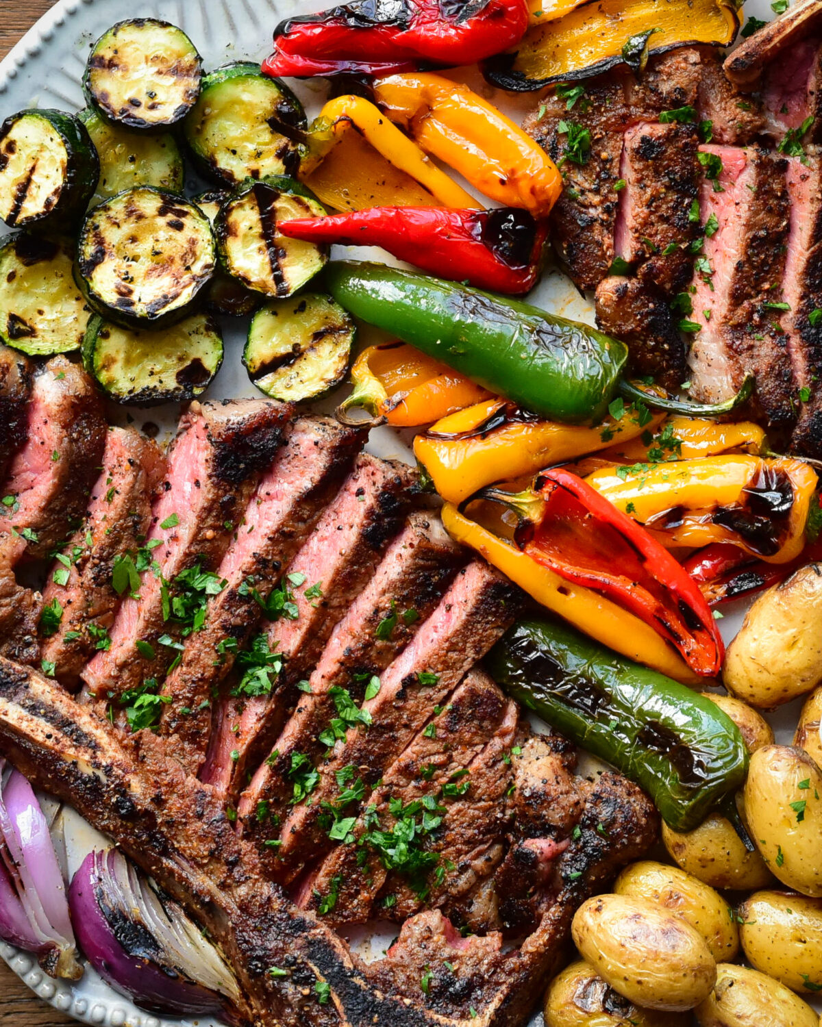 A platter of grilled veggies with sliced steak.