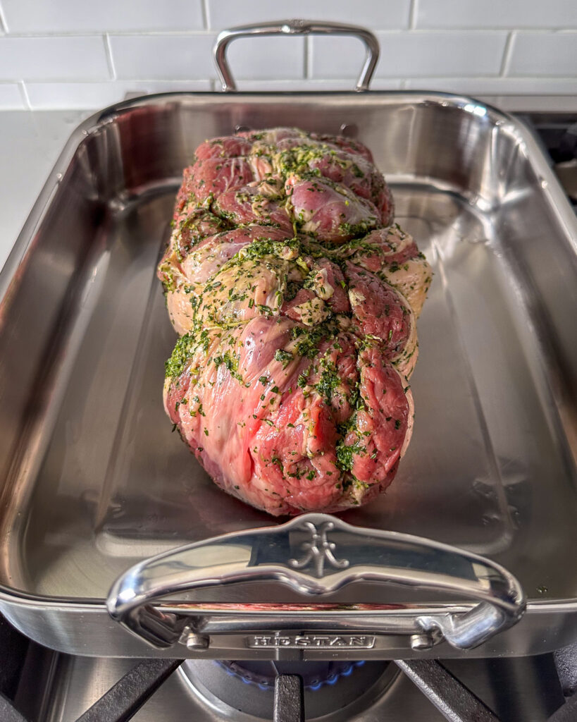 Place the rolled and tied lamb into the pan, searing it on the fatty side only.