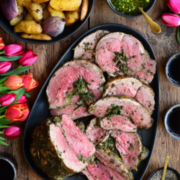 Herb Roasted Boneless Leg of Lamb served with a fresh mint sauce and roasted potatoes and onions.