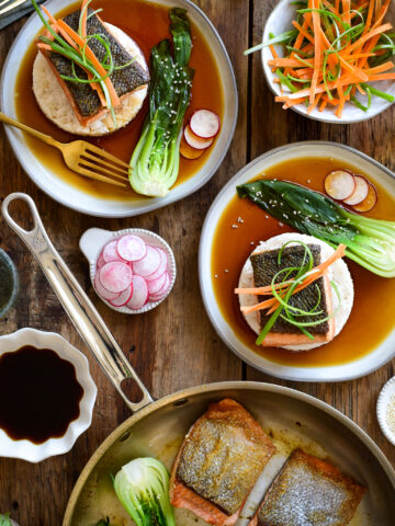 Salmon with Ponzu Sauce served on two plates with rice and bok choy served with fresh vegetable garnishes.