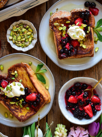 Serve the challah french toast warm with a heaping spoonful of the macerated fruit, a dollop of whipped cream, chopped pistachios, a drizzle of maple syrup and a few mint leaves.