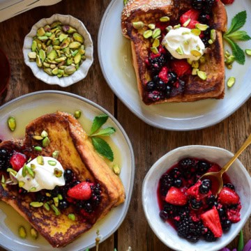 Serve the challah french toast warm with a heaping spoonful of the macerated fruit, a dollop of whipped cream, chopped pistachios, a drizzle of maple syrup and a few mint leaves.