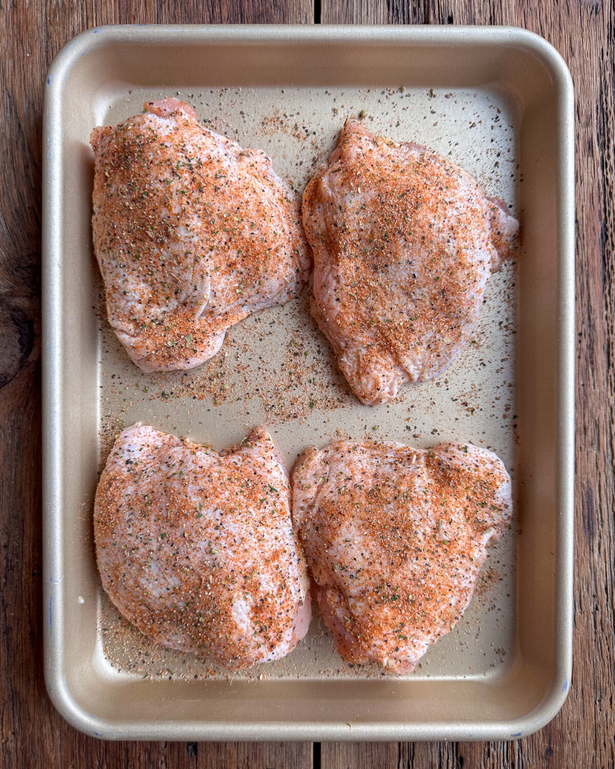 Four bone-in, skin on chicken thighs liberally seasoned with a dry rub before going into the airfryer.