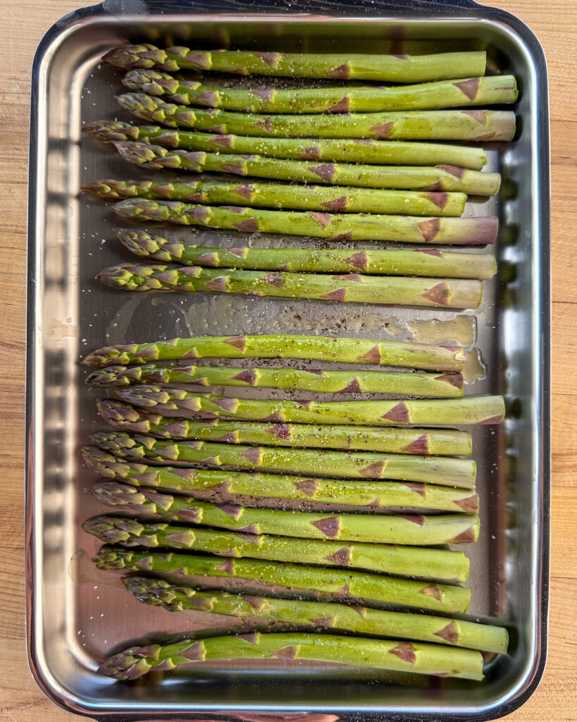 Asparagus seasoned with olive oil, salt and pepper ready to get grilled.