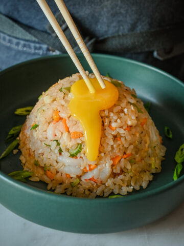 A confit egg yolk dripping down a mound of Japanese Shrimp & Egg Fried Rice.