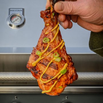 A butterflied turkey leg with grill marks and drizzed with habinero aioli sauce.