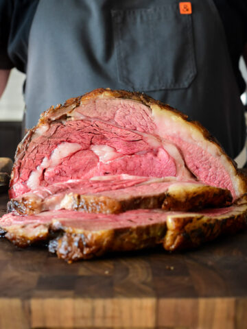 A slow roasted bone in prime rib roast slice open to reveal a perfect medium rare interior.