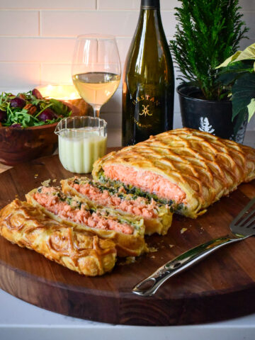 A sliced salmon en route with Leeks on a cutting board with wine and sauce.