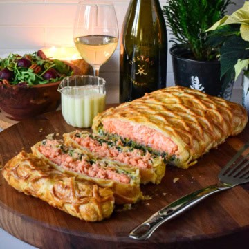 A sliced salmon en route with Leeks on a cutting board with wine and sauce.