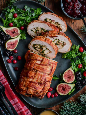 Bacon-Wrapped Stuffed Turkey Breast sliced on a platter revealing the stuffing.