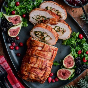 Bacon-Wrapped Stuffed Turkey Breast sliced on a platter revealing the stuffing.