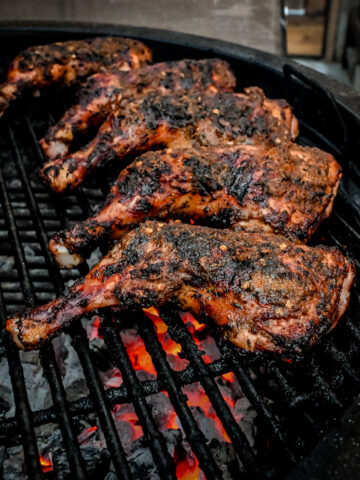 Five jerk chicken leg quarters on the BBQ.