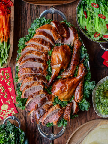 A Lunar New Year spread of a Crispy Roasted Duck - Peking Style with toppings and sides.