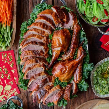 A Lunar New Year spread of a Crispy Roasted Duck - Peking Style with toppings and sides.