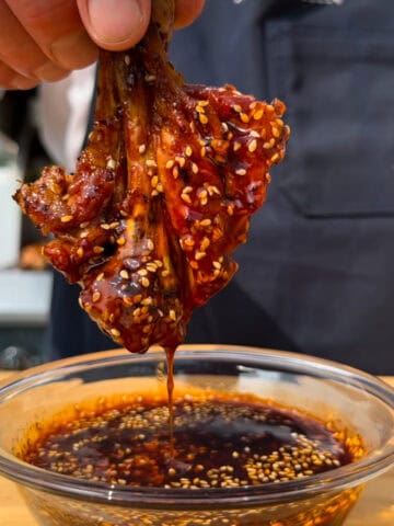 A grilled gochujang butterflied drumstick dipped into the sauce.