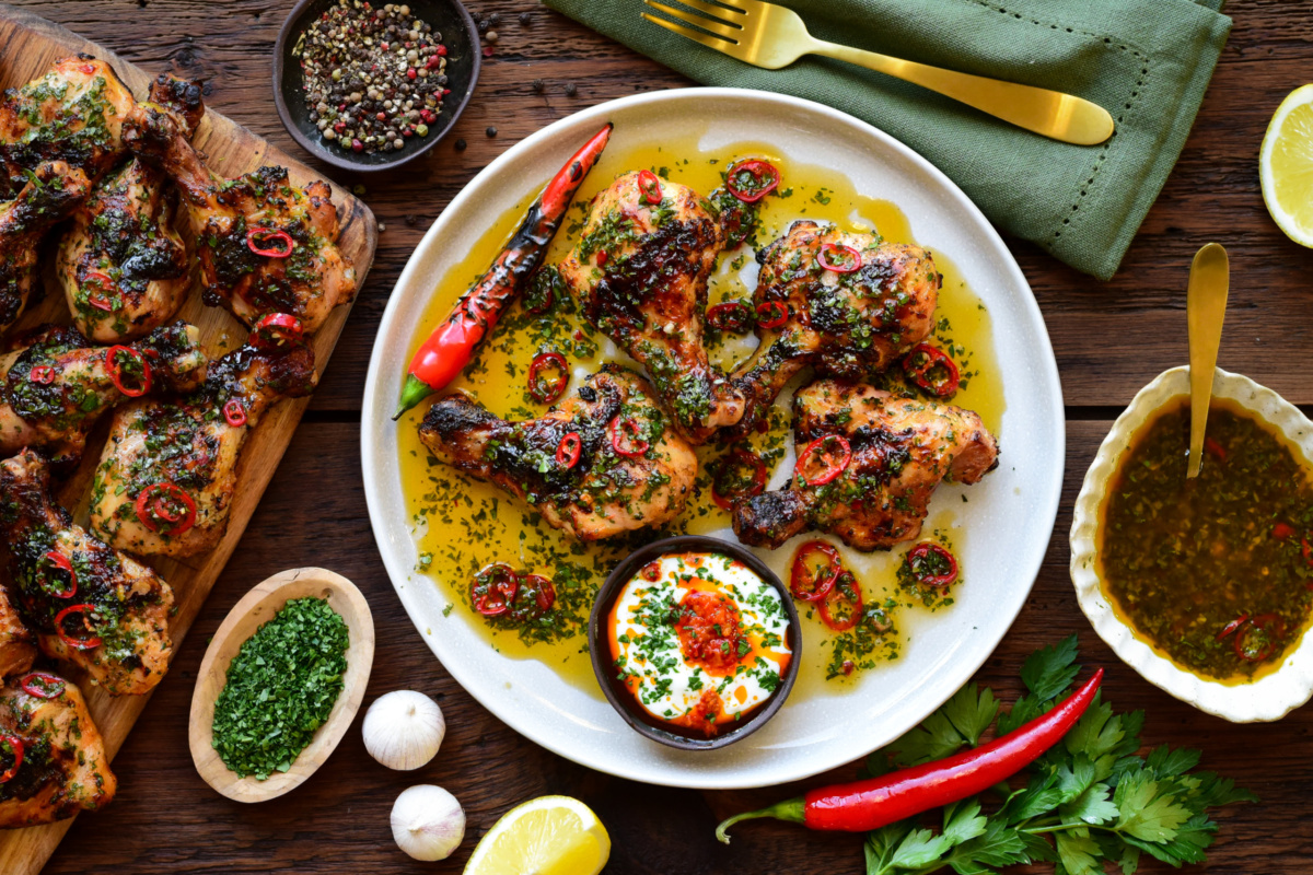 A plate of butterflied chicken drumsticks with sweet & spicy herb sauce plus extra grilled thighs.
