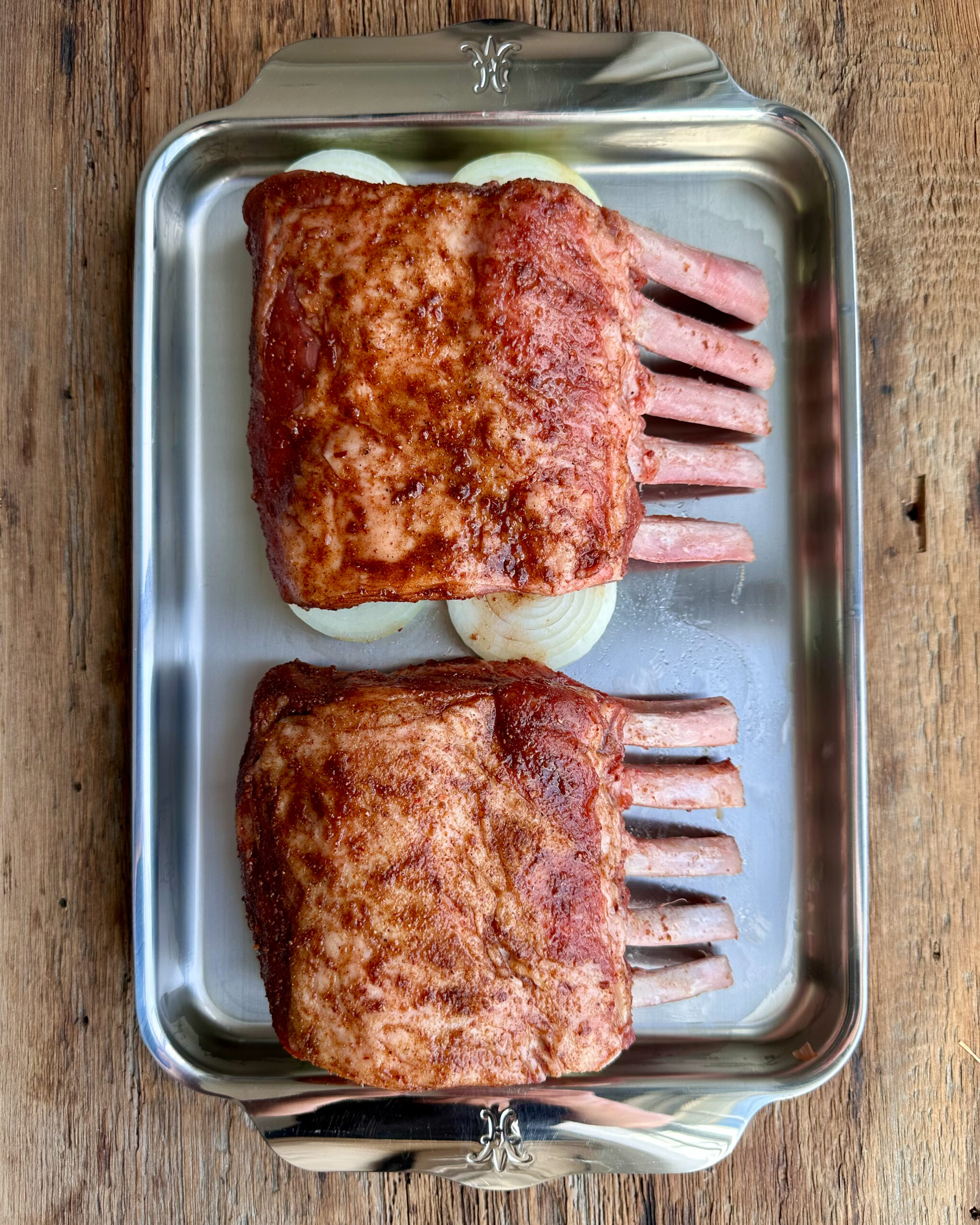 Arrange the halved onions on a small sheet pan. Place the boar racks rib-side down on top of the onions.