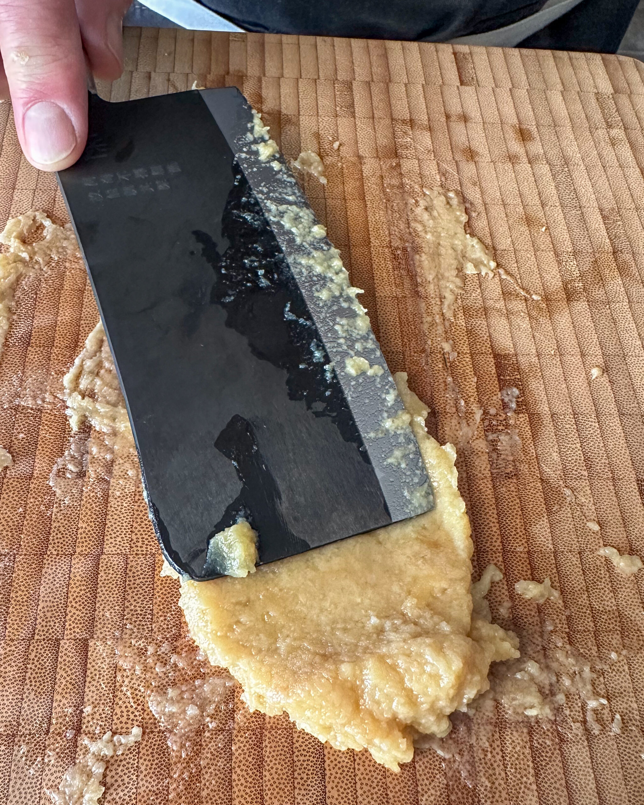 Using the flat side of a knife, spread the garlic and salt on the board. Repeat until it forms a paste.