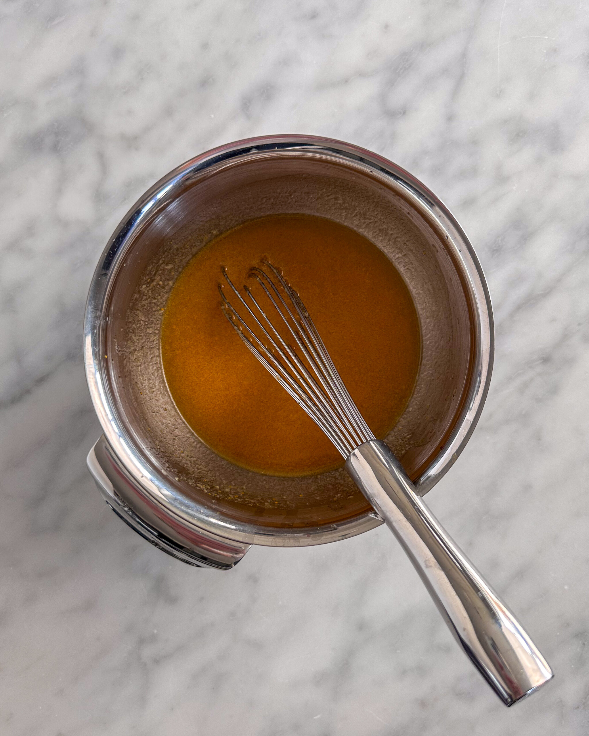 Add the garlic paste to a bowl with the grated turmeric, olive oil, honey, and charred orange juice, then whisk together until silky.