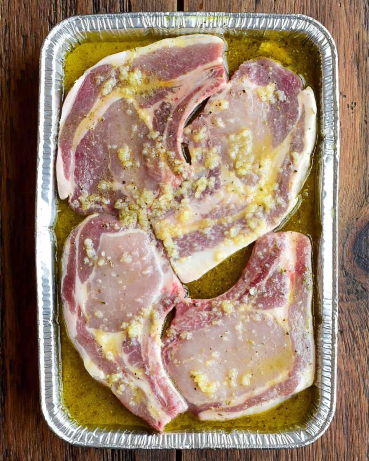 Four pork chops are marinating in a mojo marinade.