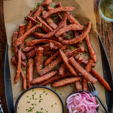 A platter of air fryer kielbasa fries with pickled onions and a spicy mustard aioli.