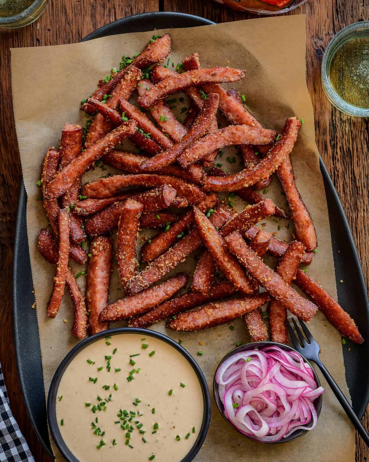 A platter of air fryer kielbasa fries with pickled onions and a spicy mustard aioli.