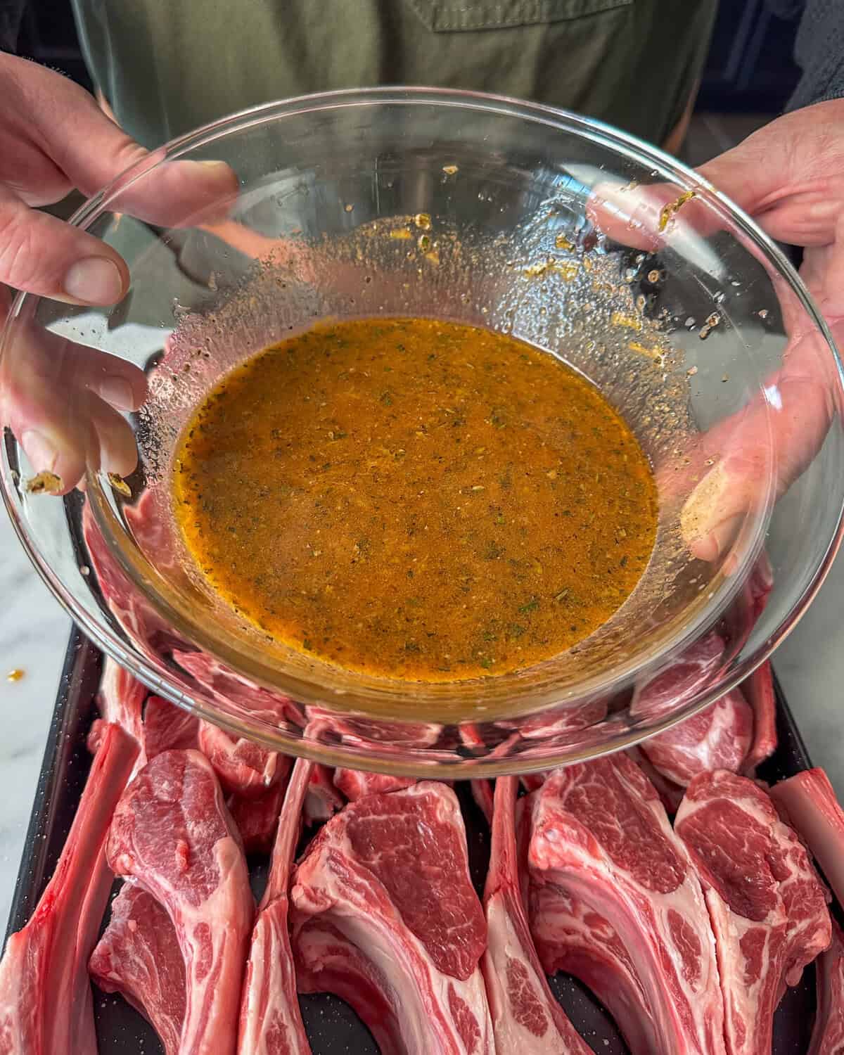 A bowl of marinade for BBQ lamb is about to be poured over the chops.