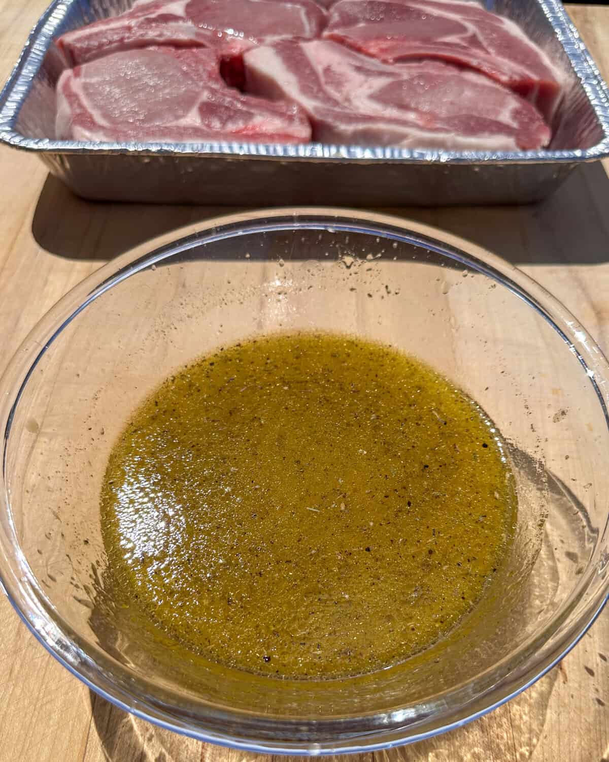 Mojo marinade in a bowl with pork chops in the background.