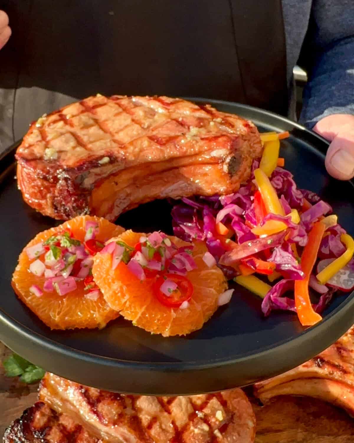 A reverse seared pork chop served with an orange salsa and a smoky mojo red cabbage slaw.
