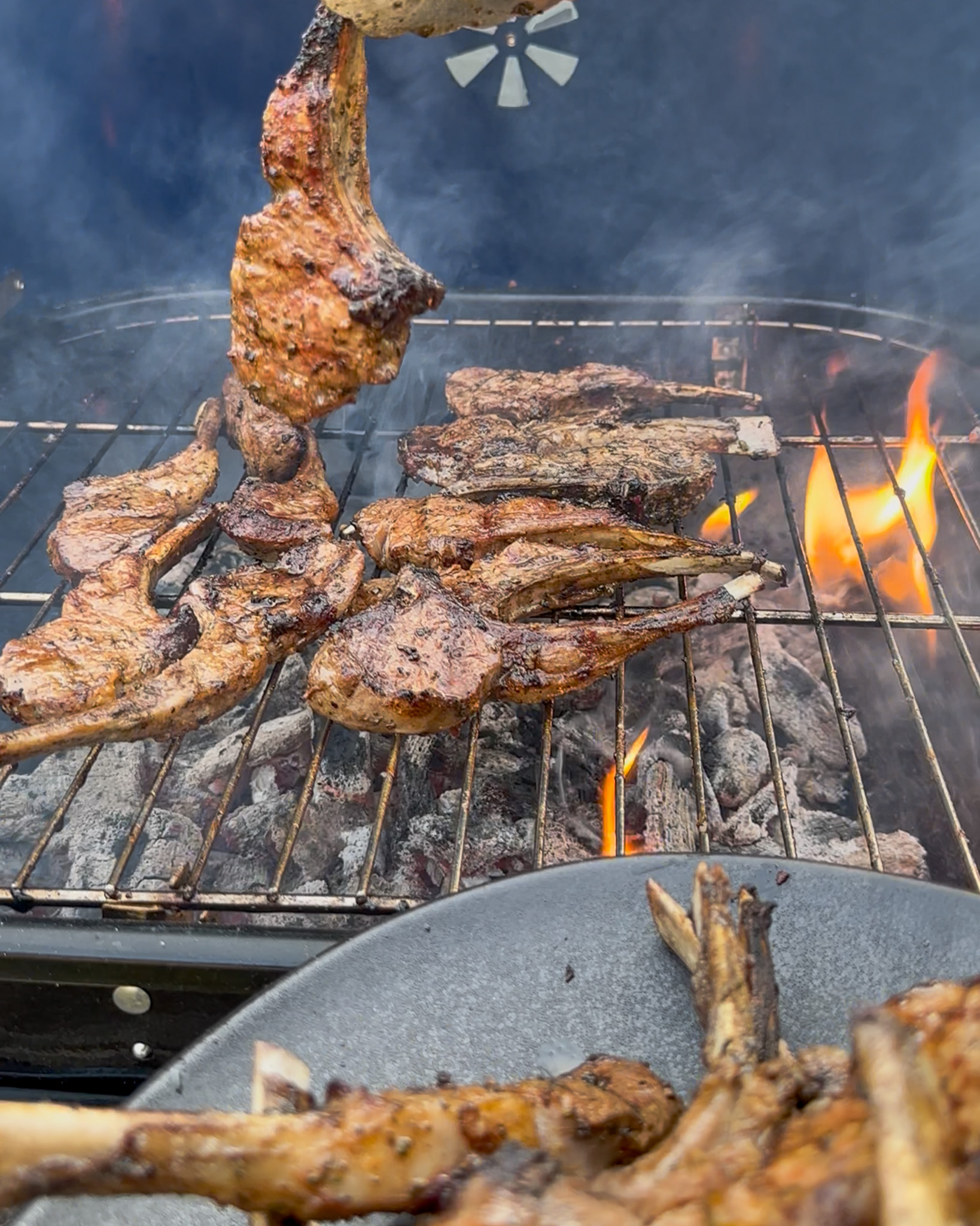 Lamb chops coming off a BBQ with flames.