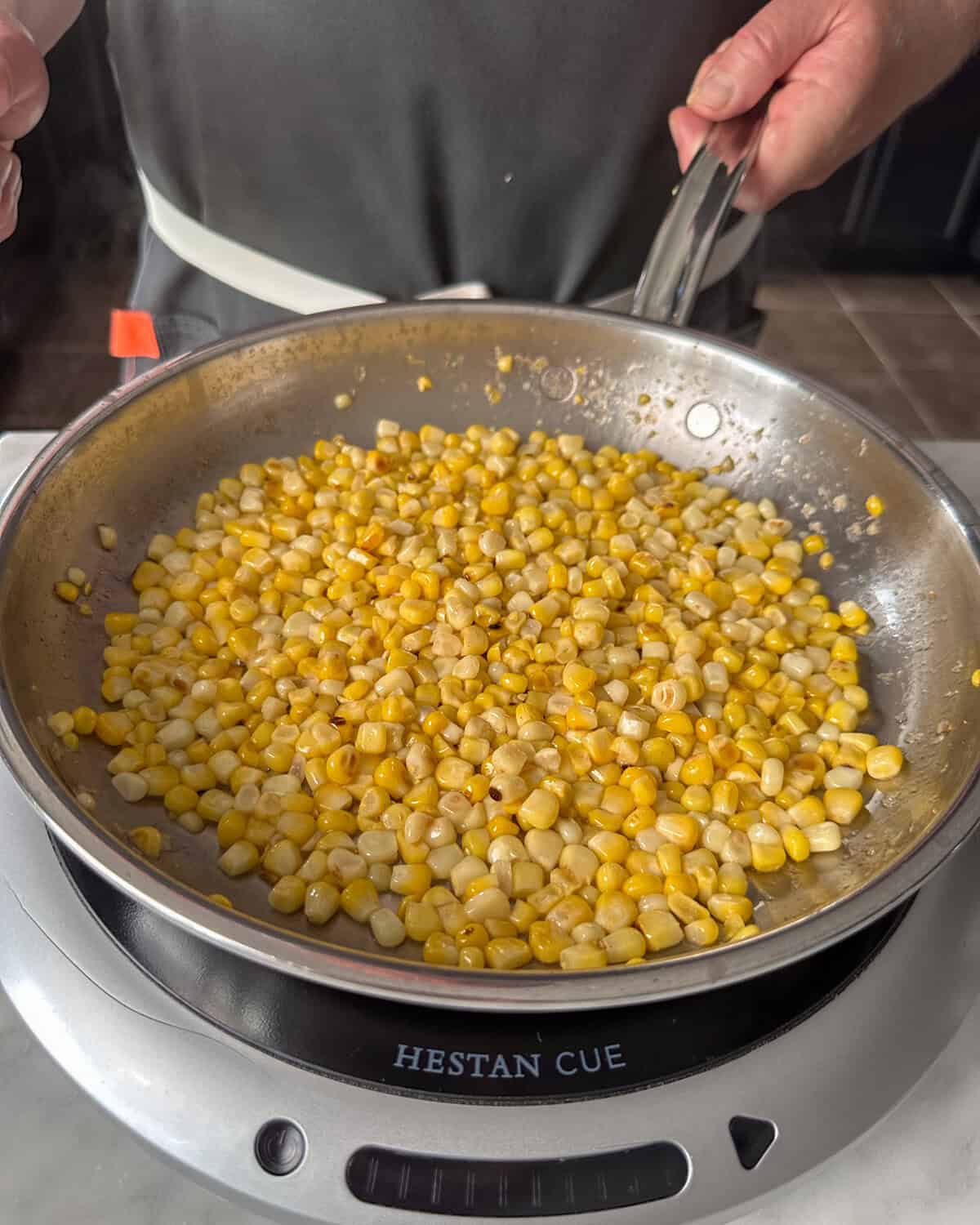 A skillet of corn is getting cooked for an elote salsa.