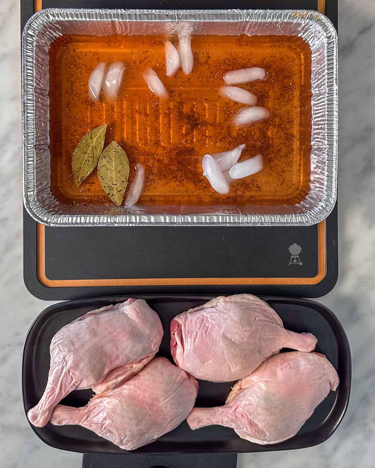 A foil pan with a brining solution for smoked duck legs.