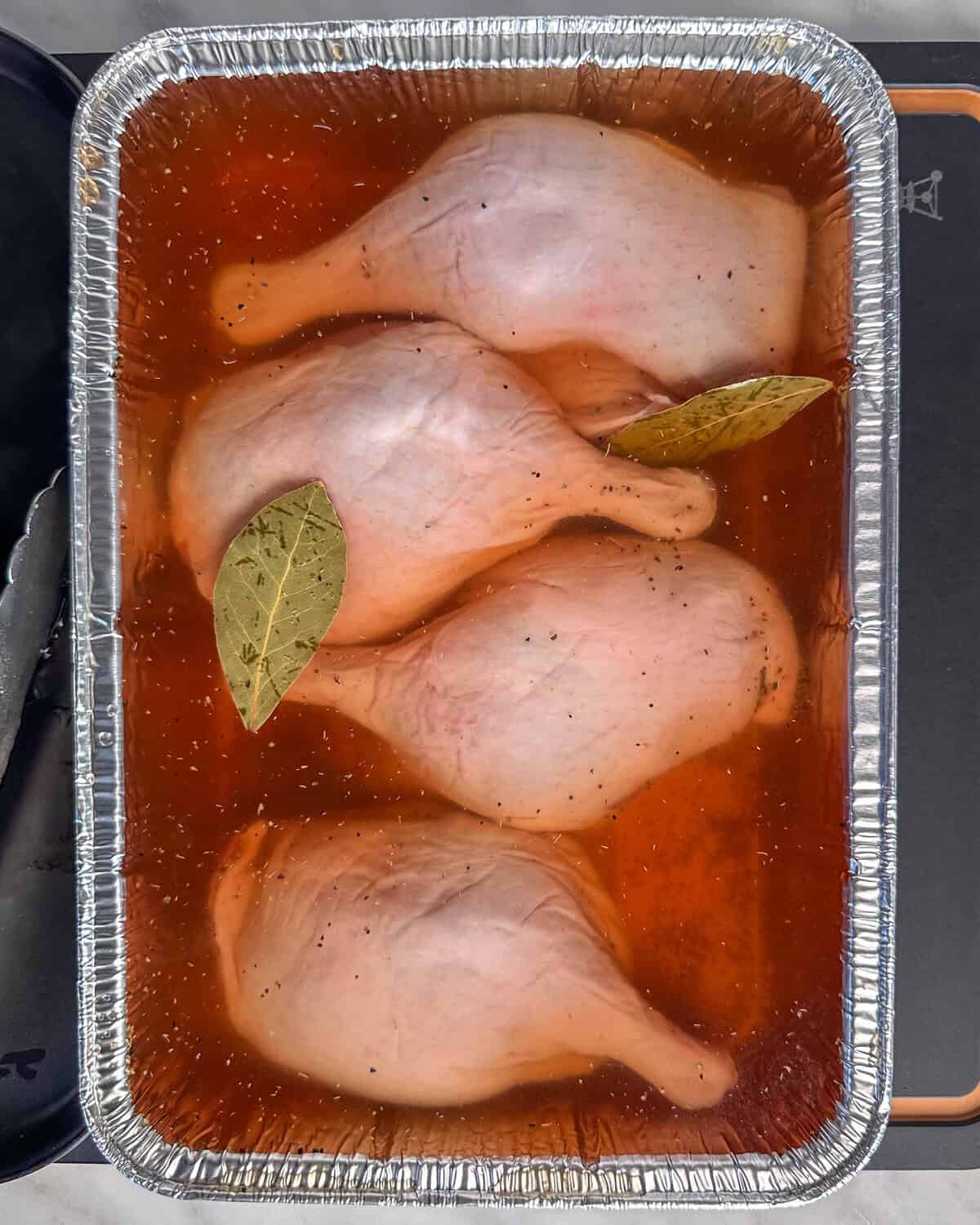Four duck legs are brining in a tea brine before getting smoked.
