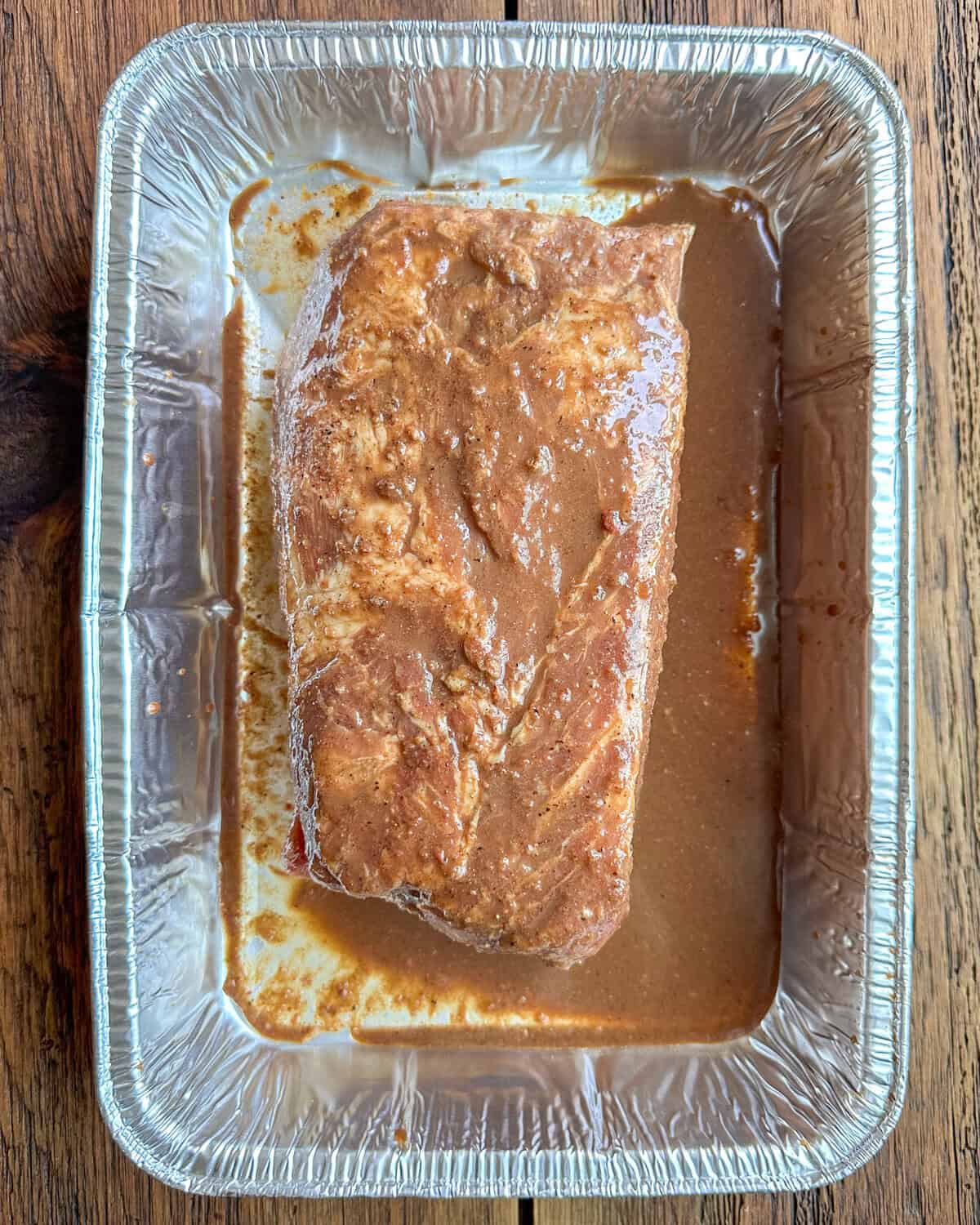 Char siu marinated pork coppa in a foil pan.
