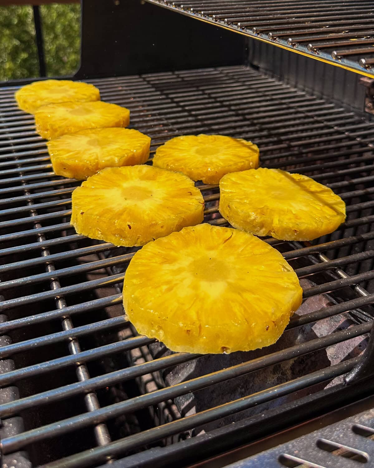 Seven pineapple rings on the grill for a pineapple relish recipe.