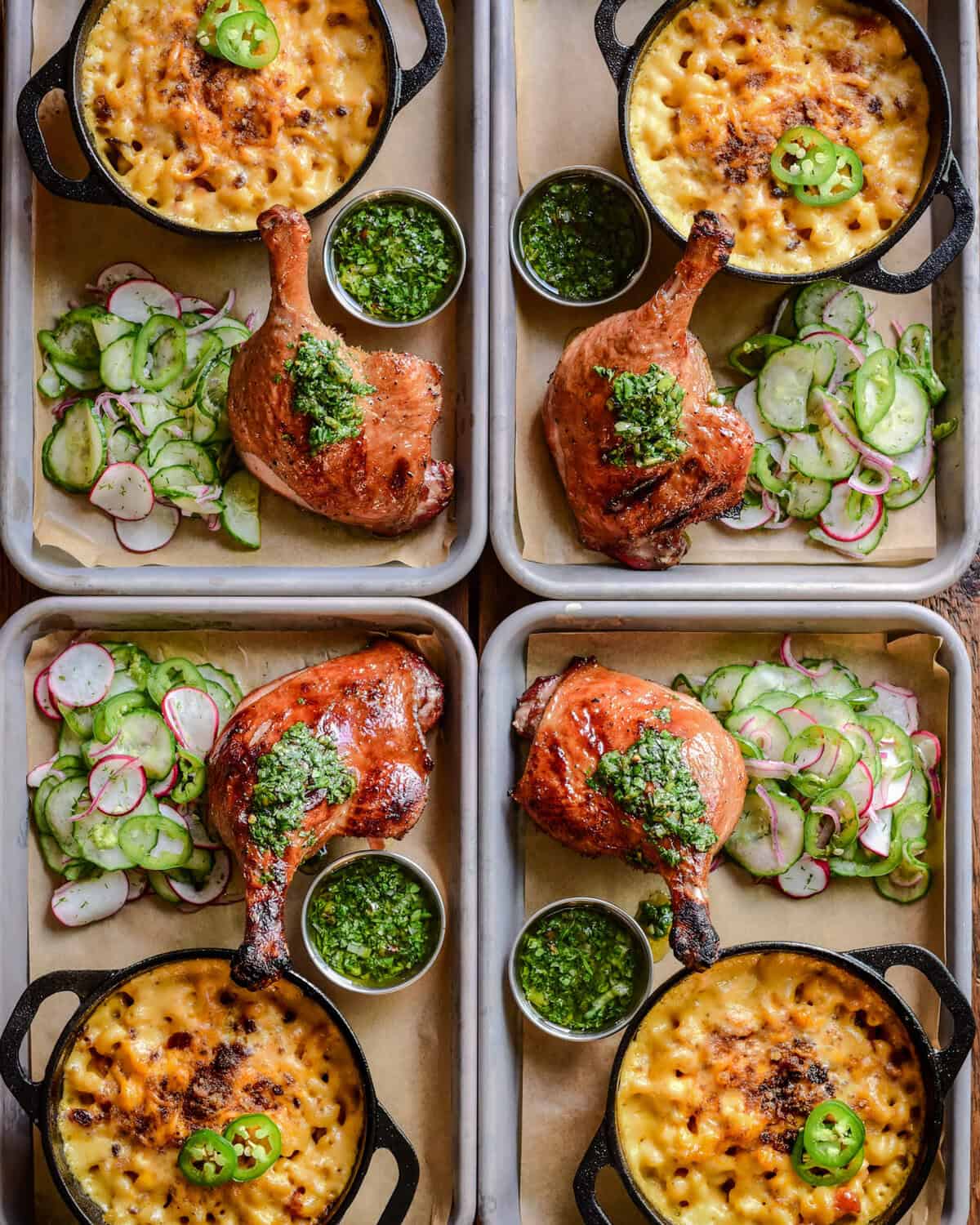 Four personal sized trays, each with a smoked duck leg, sauce, mac & cheese and a cucumber salad.