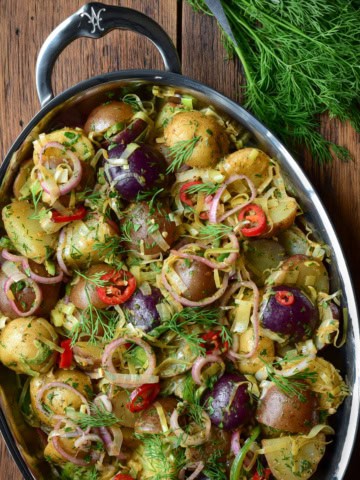 A Brown Butter Potato Salad with Leeks & Pickled Shallots on an oval platter and served with fresh dill.
