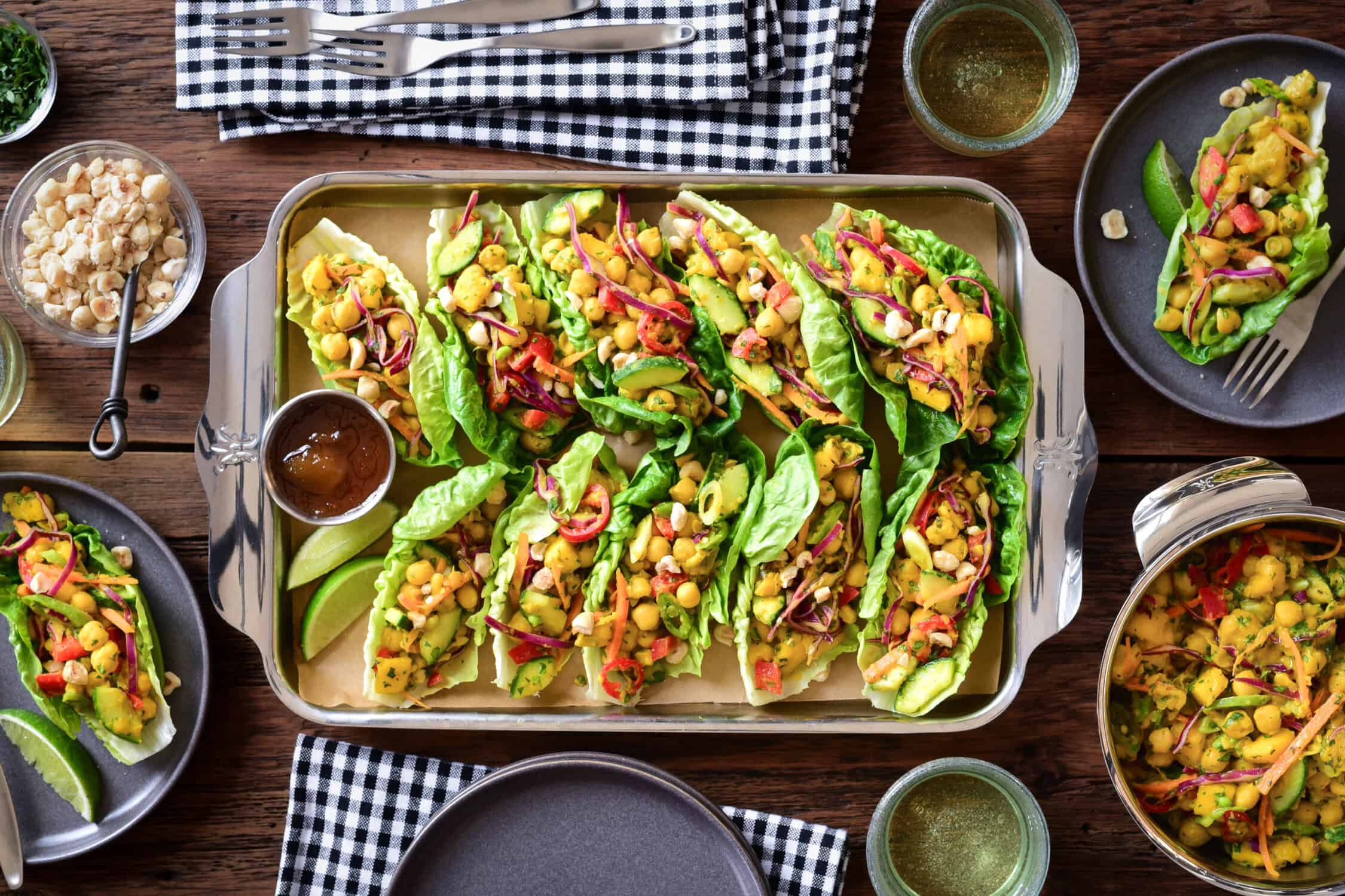 A tray of Curried Coconut Chickpea and Mango Salad lettuce wraps. Served on small plates and a bowl with extra curry. 