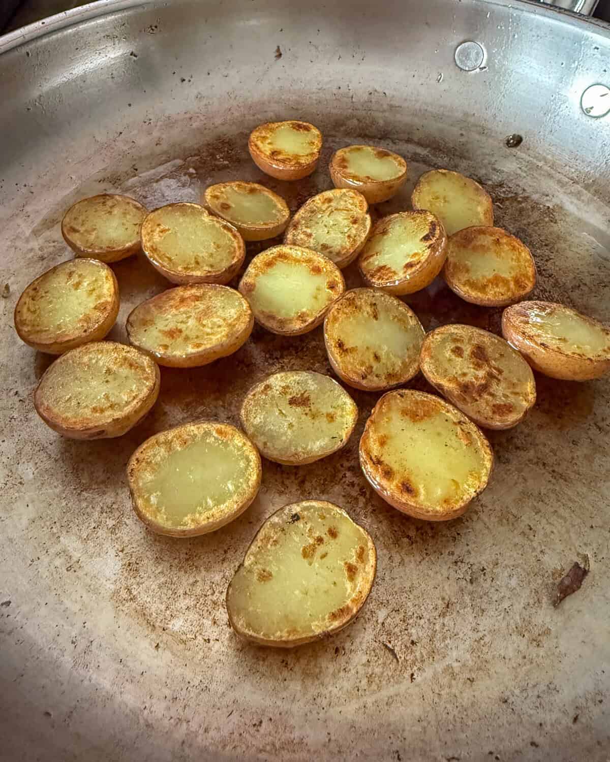 Sear the potatoes, cut side down.