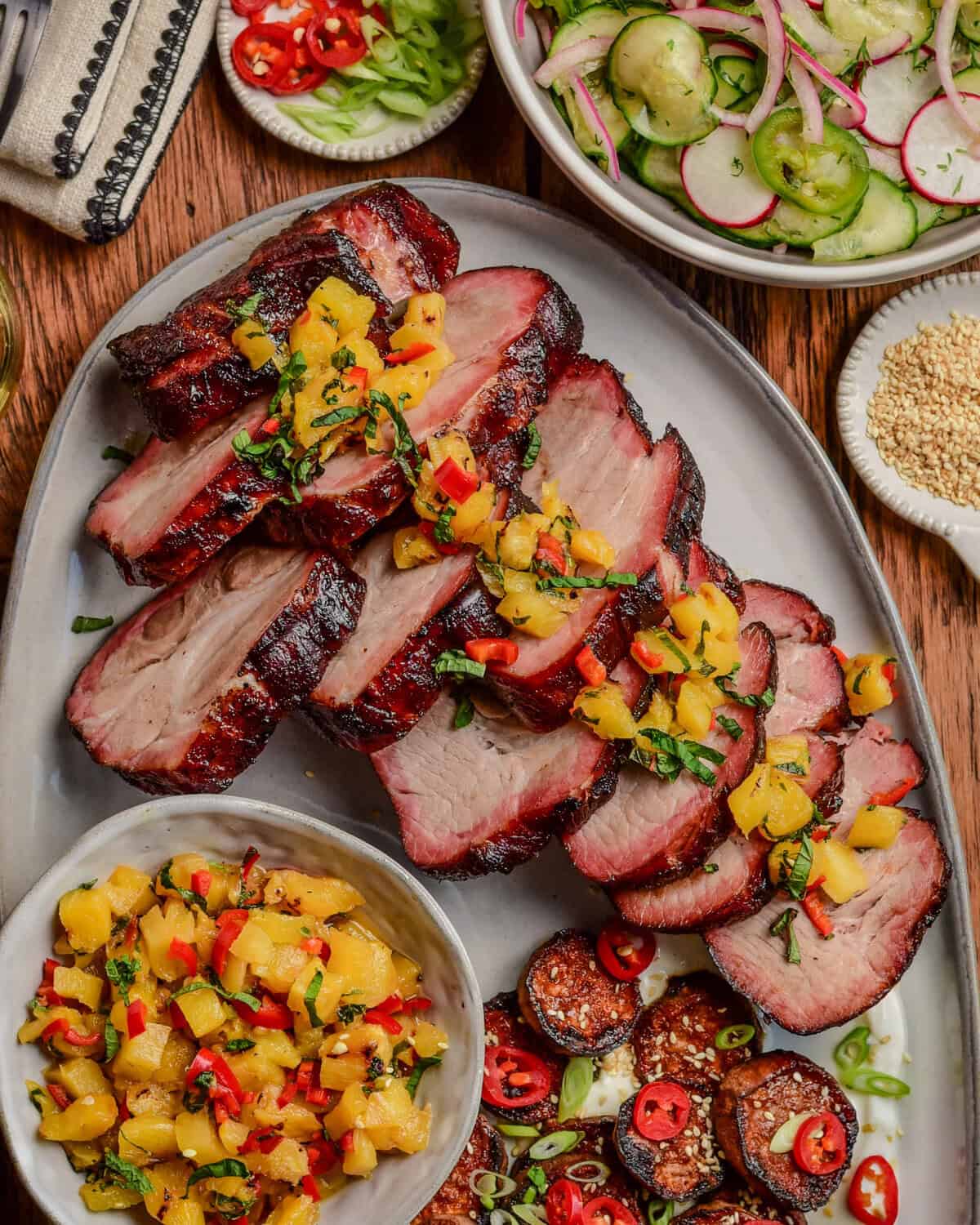 Slices of smoked char siu pork with a pineapple relish overtop and served with a cucumber salad and sweet potatoes.