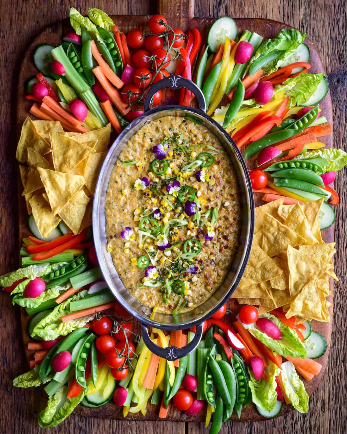 Charred Corn, Poblano and Jalapeño Dip in an oval au gratin. Served with a colourful variety of veggies and tortilla chips.