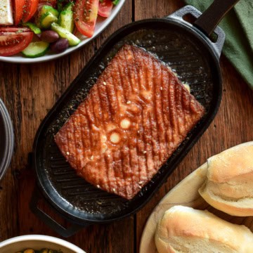 Greek kefalotyri cheese in a cast-iron skillet served with a Greek village salad and crusty bread.