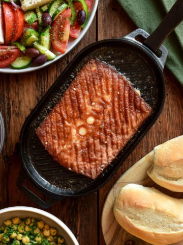 Greek kefalotyri cheese in a cast-iron skillet served with a Greek village salad and crusty bread.
