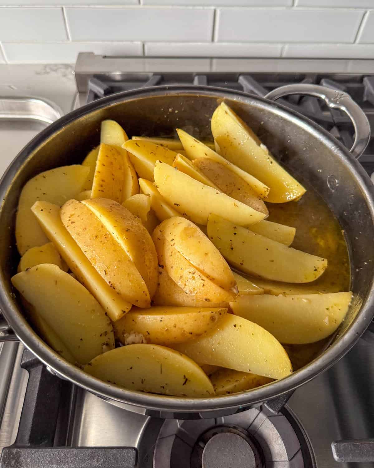 Greek style potato wedges in a pot with a braising liquid.