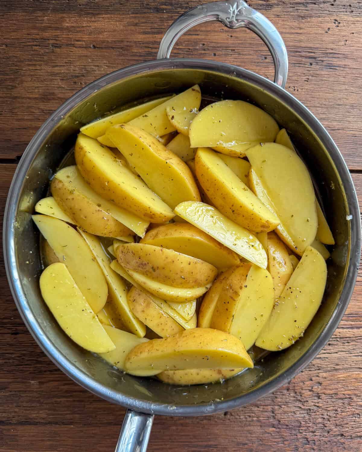 Greek potato wedges in a pot are about to get braised.