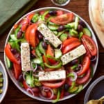 A Greek Village Salad (Horiatiki Salata) with four pieces of feta on top.